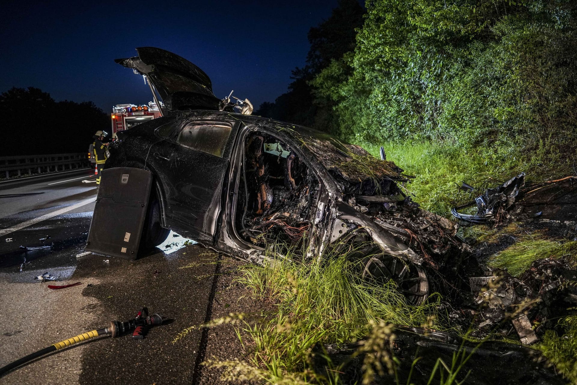 Der komplett ausgebrannte Porsche liegt am Straßenrand: Die Löscharbeiten gestalteten sich für die Feuerwehrleute schwierig.