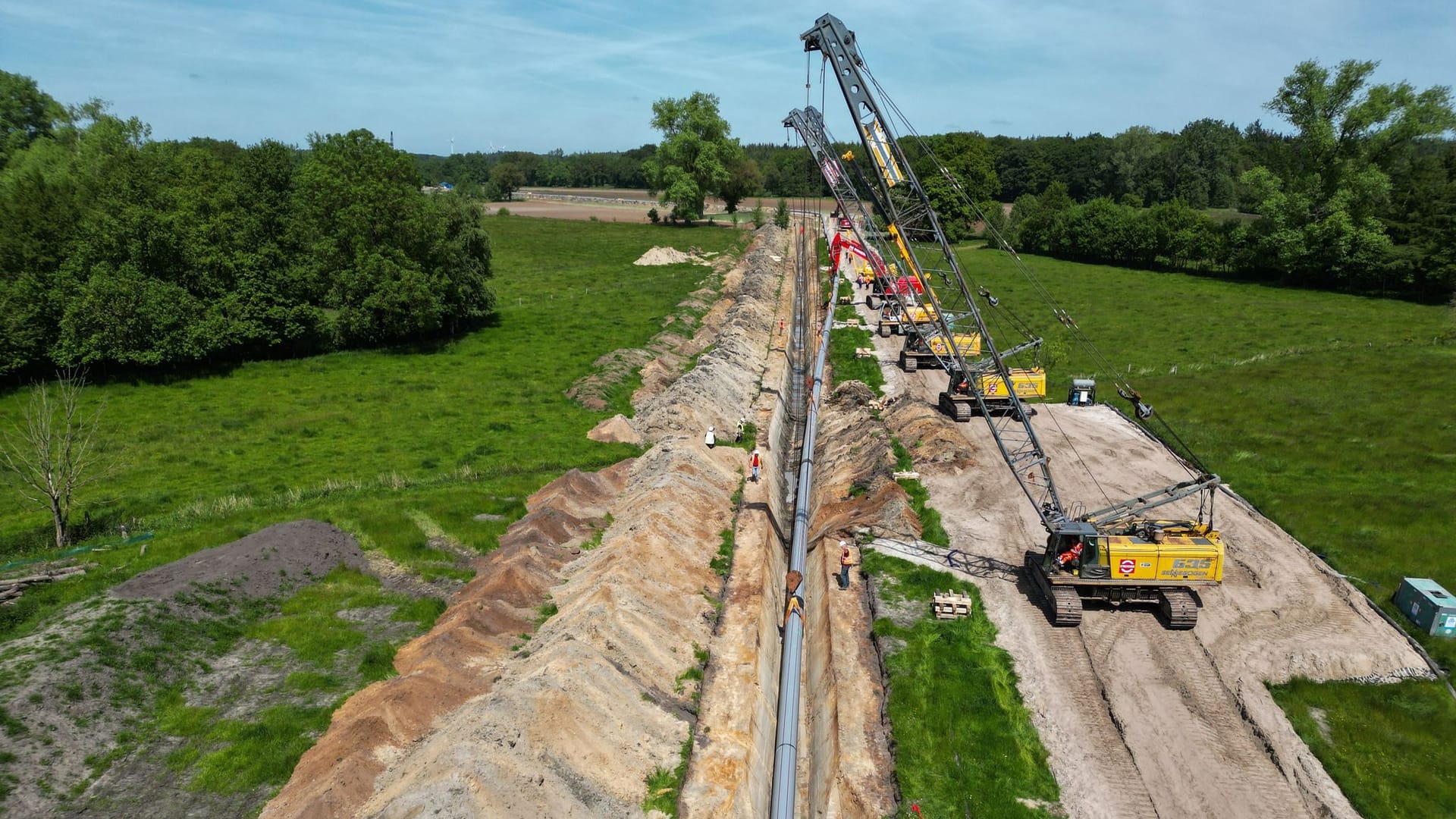 Große Baukräne hieven die Pipeline in den Rohrgraben. Für eine weitere Anbindungspipeline an das LNG-Terminal in Wilhelmshaven kommen im Ammerland die Bauarbeiten voran.