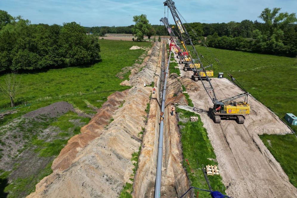 Große Baukräne hieven die Pipeline in den Rohrgraben. Für eine weitere Anbindungspipeline an das LNG-Terminal in Wilhelmshaven kommen im Ammerland die Bauarbeiten voran.