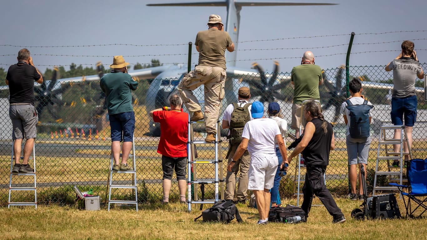 Planespotter stehen an einem Zaun vor dem Fliegerhorst Wunstorf und fotografieren einen Airbus A400M der Luftwaffe.