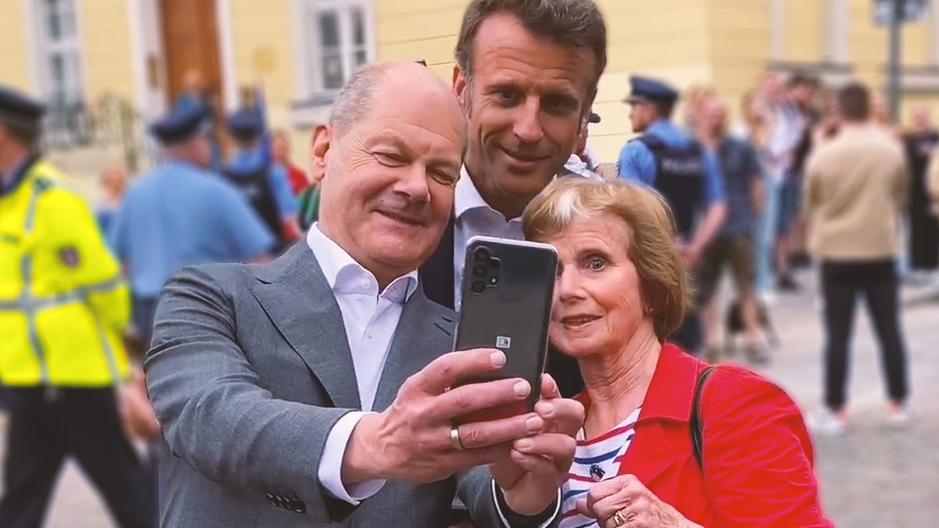 Macron und sein Amtskollege Scholz posieren beim Besuch in Potsdam mit Bürgern für Fotos.