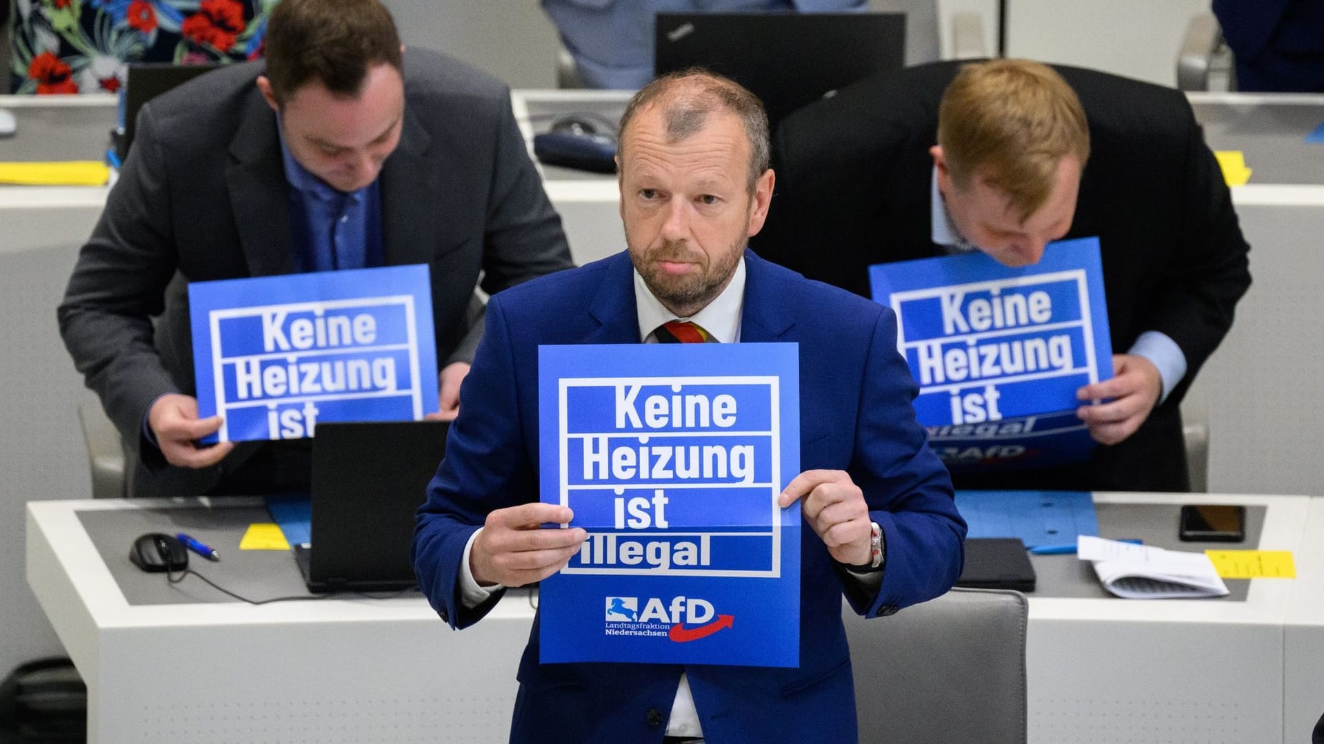 Stefan Marzischewski-Drewes (AfD) und weitere Fraktionsmitglieder im niedersächsischen Landtag: Während der Debatte halten sie Schilder mit der Aufschrift "Keine Heizung ist illegal" hoch.