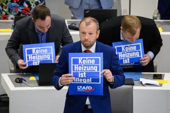 Stefan Marzischewski-Drewes (AfD) und weitere Fraktionsmitglieder im niedersächsischen Landtag: Während der Debatte halten sie Schilder mit der Aufschrift "Keine Heizung ist illegal" hoch.