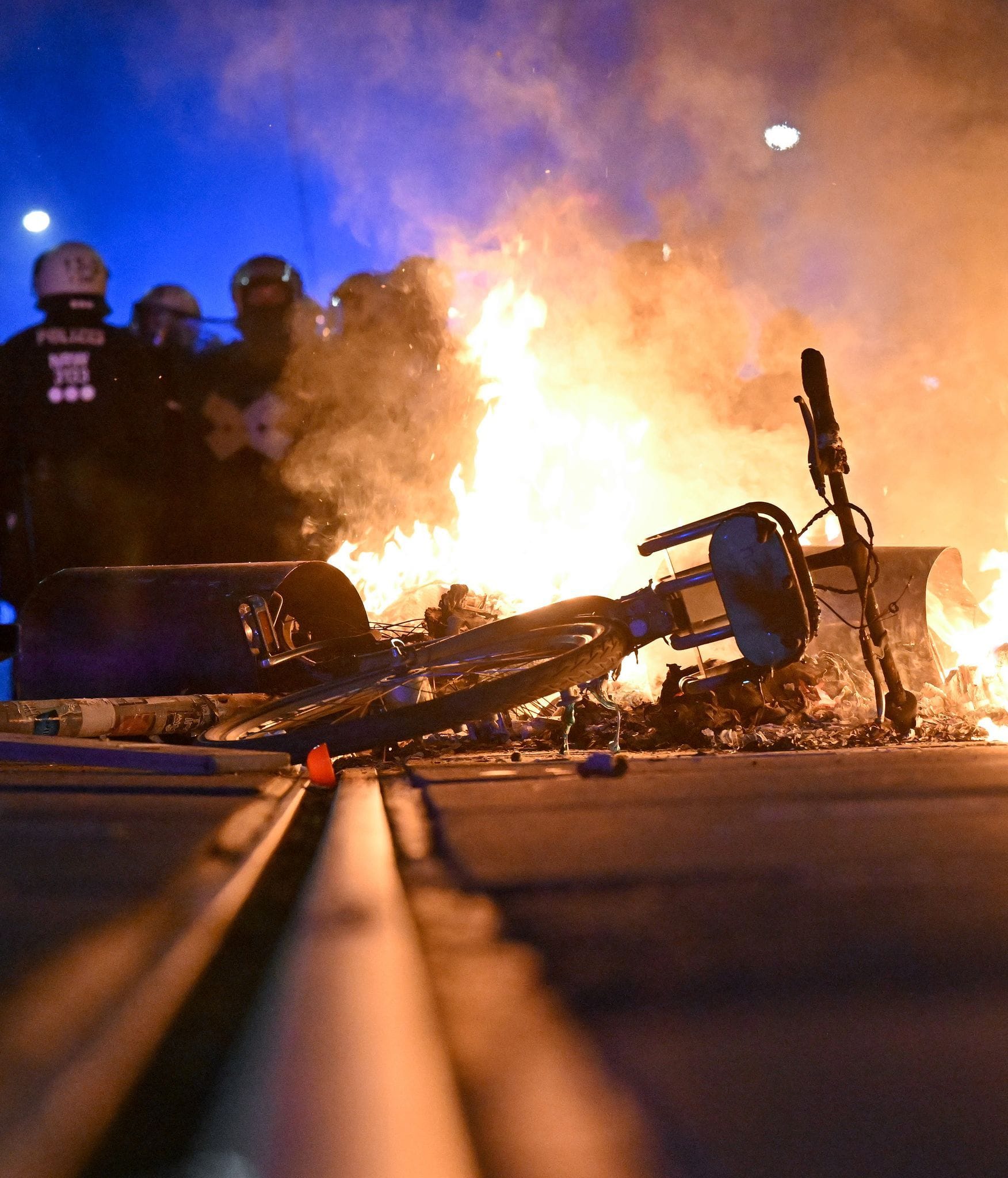 Eine Barrikade brennt im Stadtteil Connewitz in Leipzig. Polizisten stehen im Hintergrund.