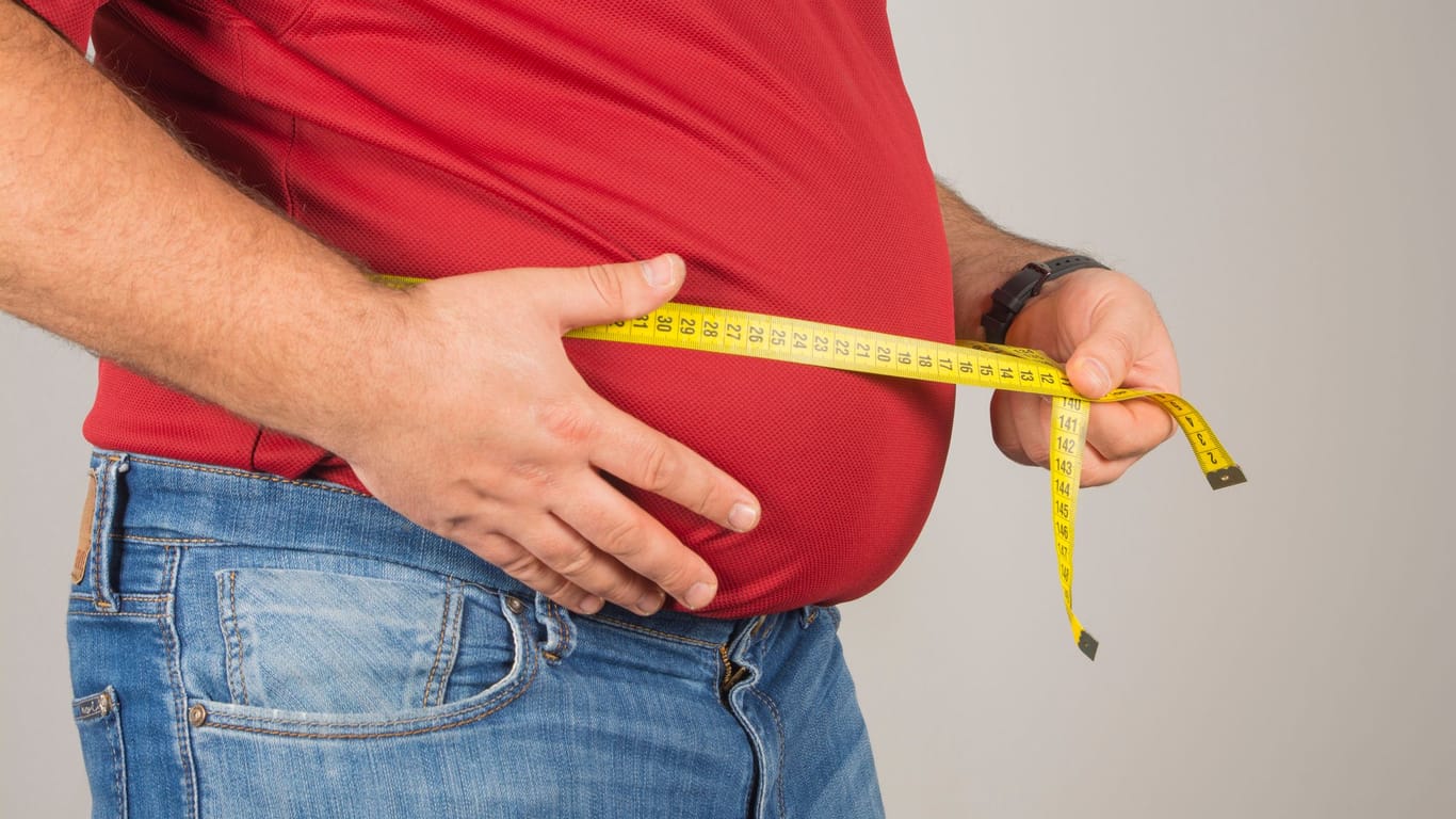 Übergewichtiger Mann misst den Bauchumfang: Hohes Gewicht kann Herz-Kreislauf-Erkrankungen begünstigen