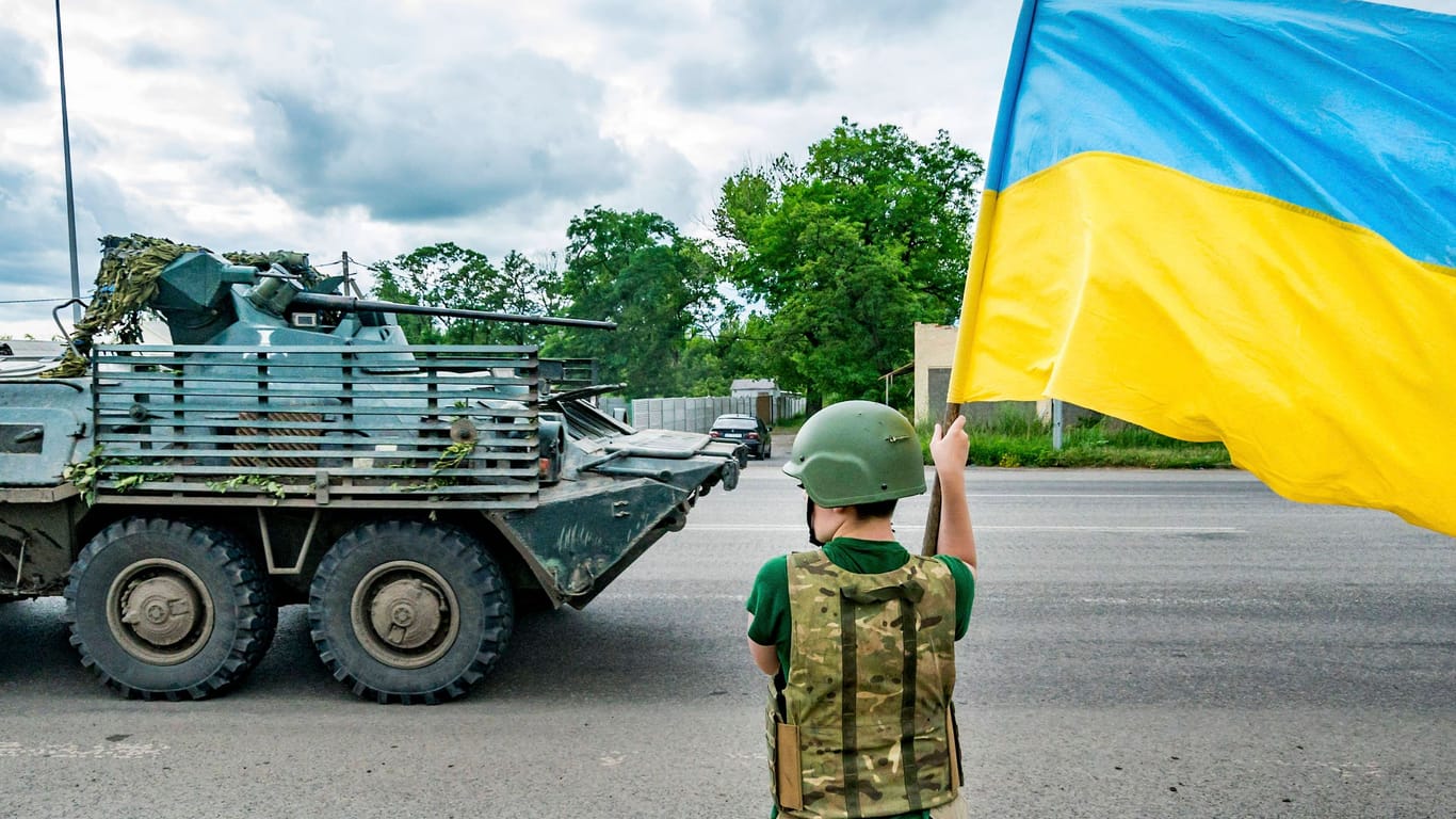 Ein Kind steht mit einer ukrainischen Fahne in der Hand nahe Bachmut und winkt ukrainischen Soldaten zu (Archivbild).