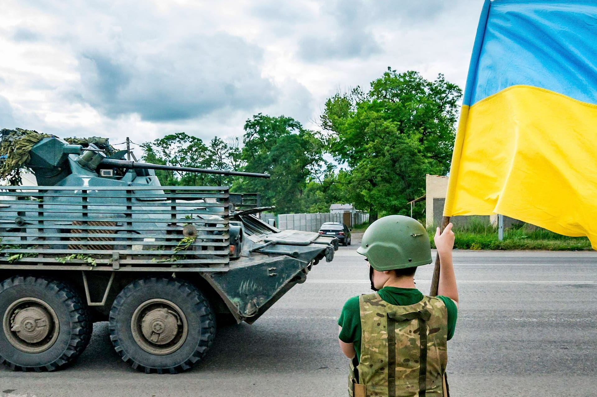 Ein Kind steht mit einer ukrainischen Fahne in der Hand nahe Bachmut und winkt ukrainischen Soldaten zu (Archivbild).