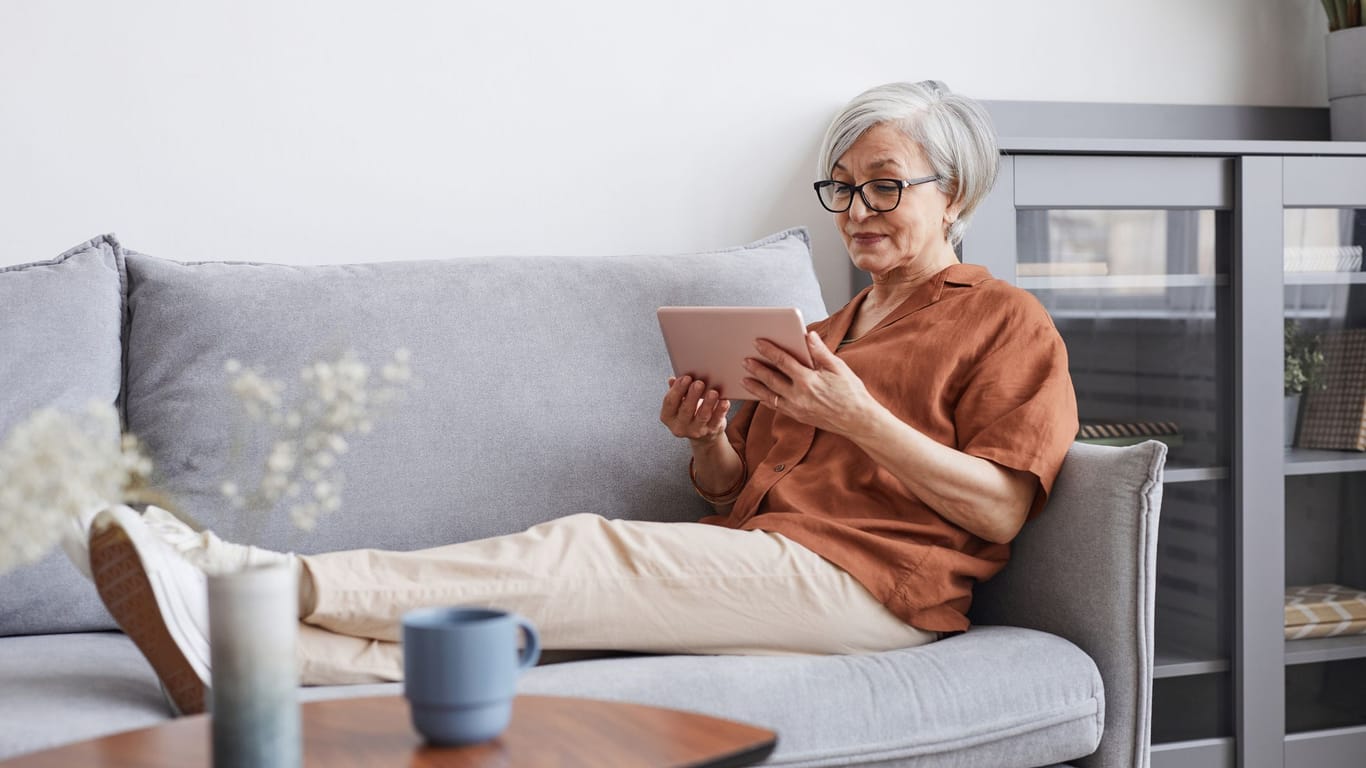 Ältere Frau entspannt auf der Couch (Symbolbild): Es gibt einige Tricks, früher in Rente zu gehen, ohne auf allzu viele Bezüge verzichten zu müssen.