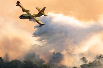 Kroatien, Ciovo: Ein Löschflugzeug versprüht Wasser, um einen Waldbrand auf der Insel Ciovo zu löschen.