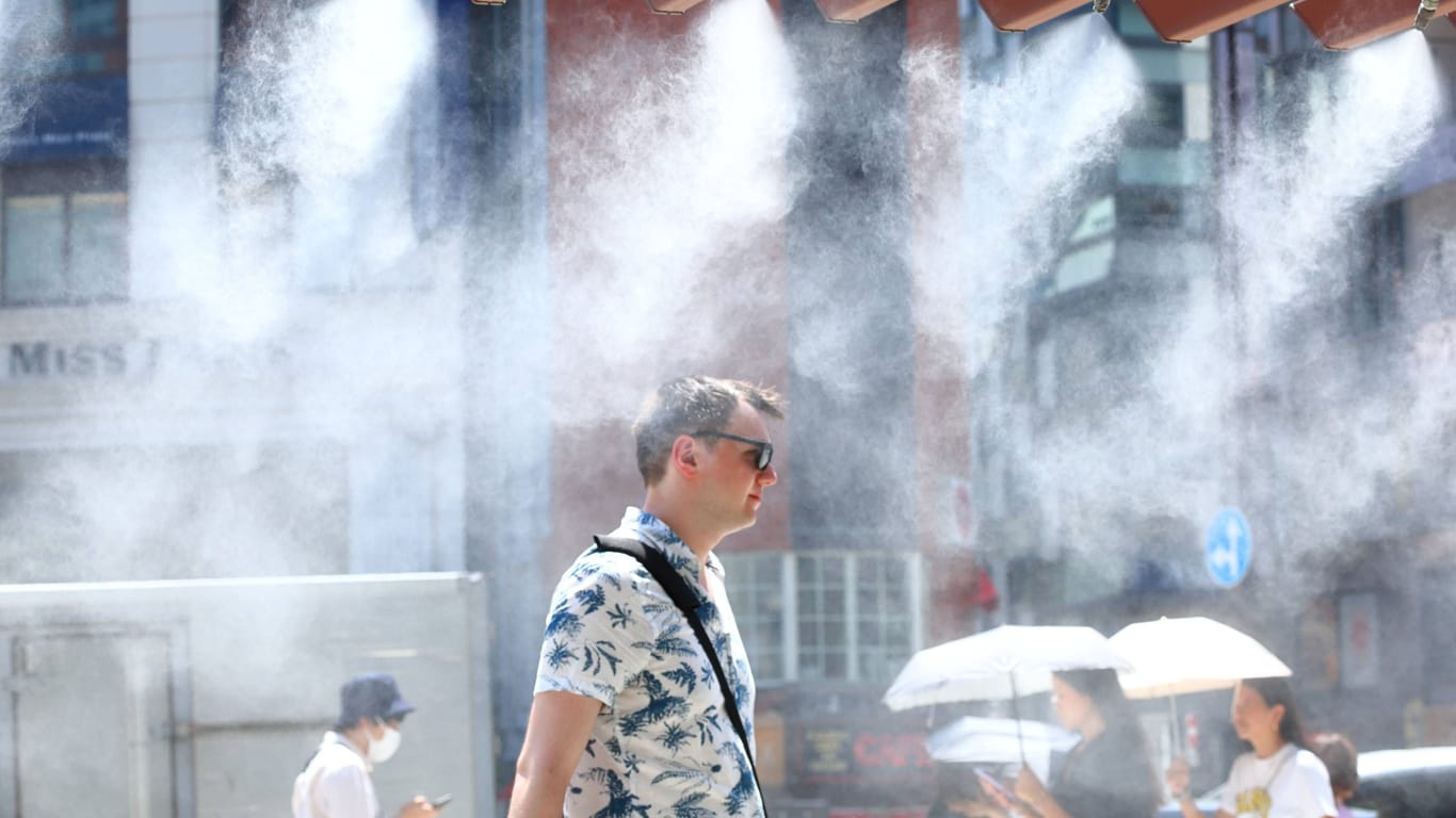 Ein Mann in tokyo erfrischt sich während einer Hitzewelle unter einem Wasservernebler. Mitte Juli herrschten in der Megametropole tagelang knapp 40 Grad.
