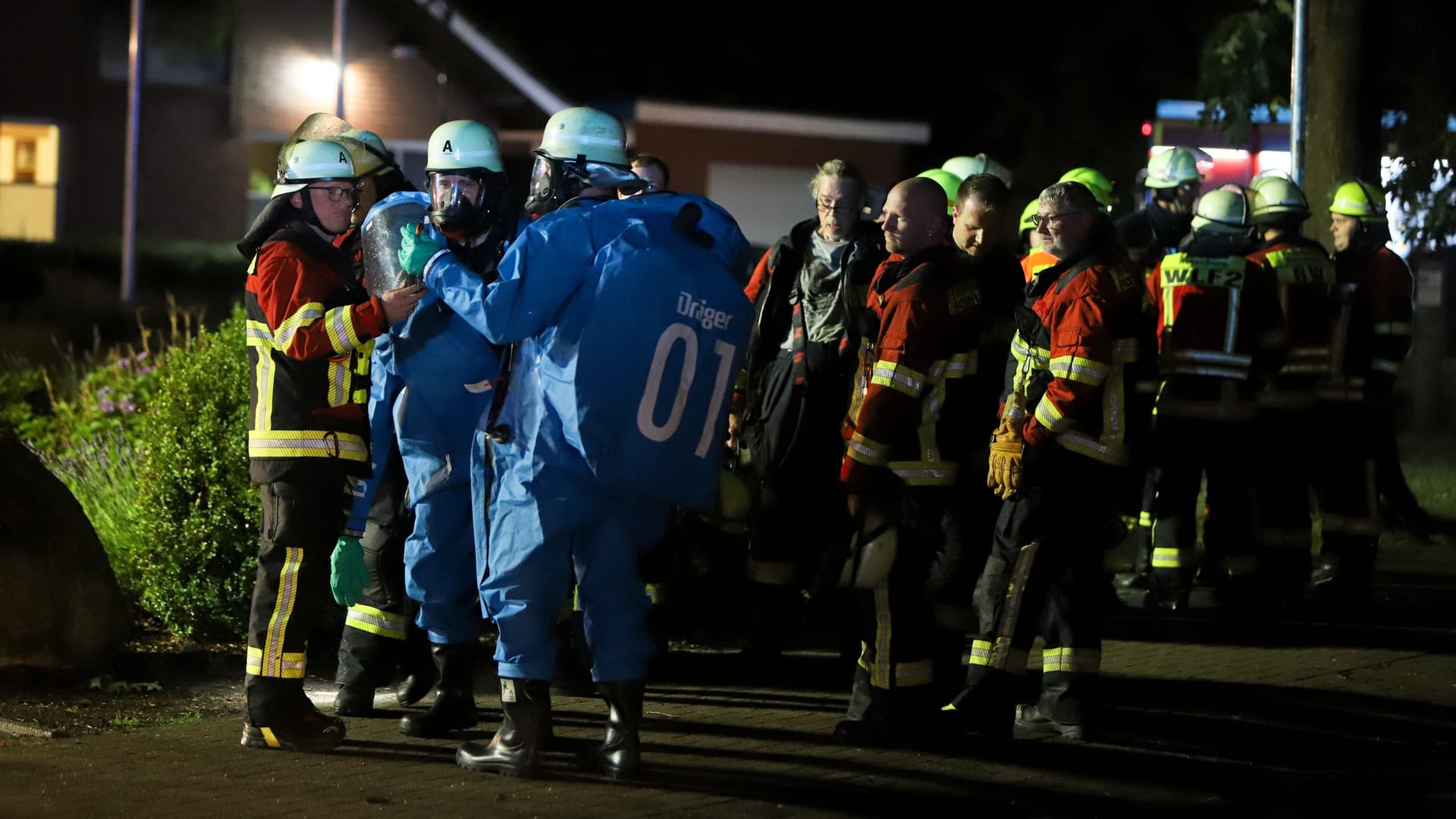 Einsatzkräfte der Feuerwehr ziehen sich spezielle Schutzanzüge an. Zuvor war ein Blitz in das Technikhaus des Freibades Bothel eingeschlagen. Einsatzkräfte der Feuerwehr ziehen sich spezielle Schutzanzüge an. Zuvor war ein Blitz in das Technikhaus des Freibades Bothel eingeschlagen.