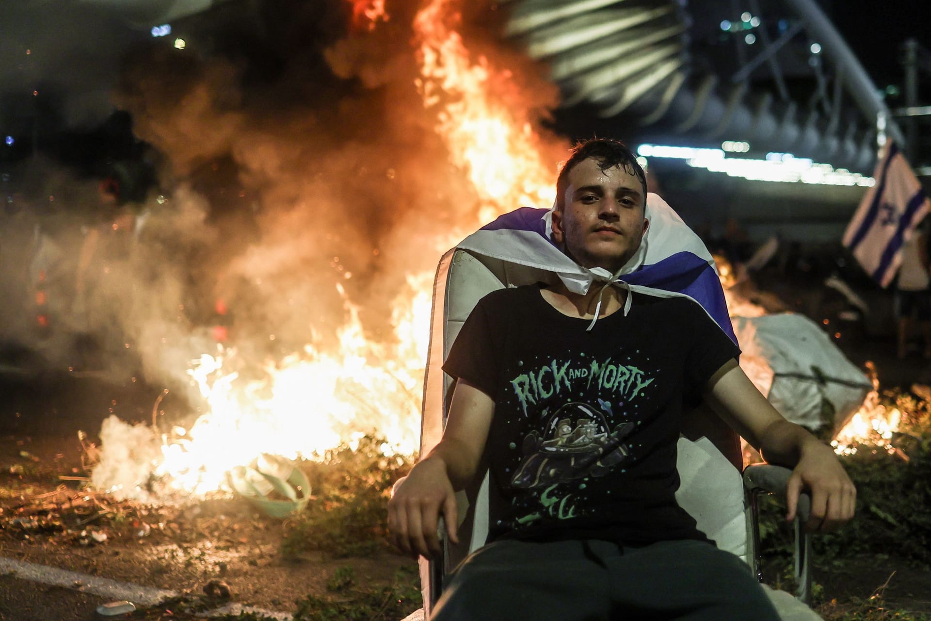 Ein israelischer Demonstrant sitzt vor einem Feuer auf den Straßen Tel Avivs: Die Proteste gegen die Selbstermächtigung der israelischen Regierung brechen nicht ab.