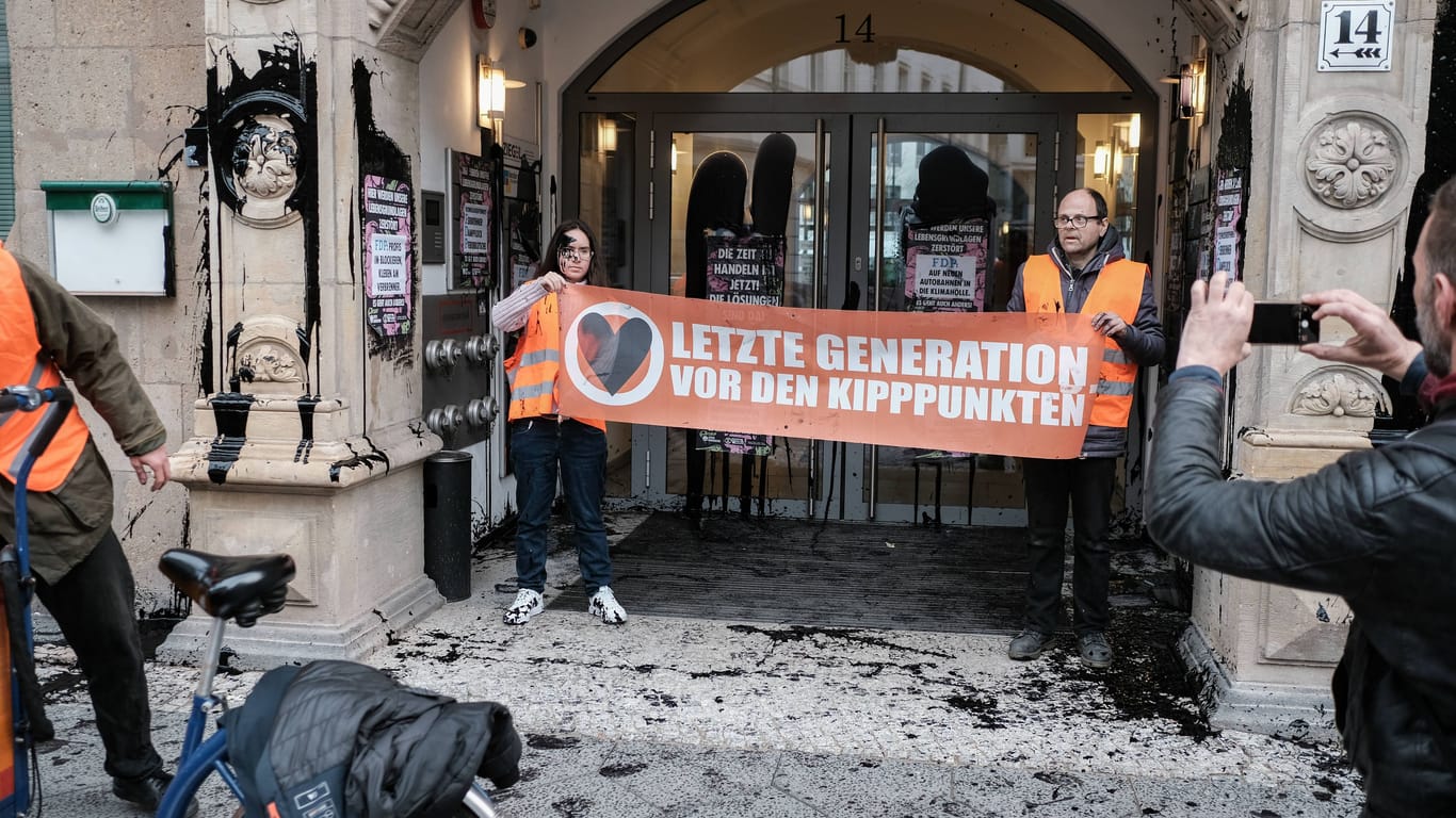 Vor der FDP-Parteizentrale halten Mitglieder der Letzten Generation ein Banner in die Höhe
