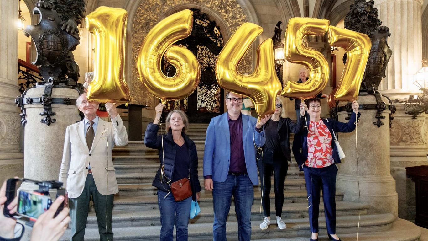 Mitglieder der Volksinitiative "Schluss mit Gendersprache in Verwaltung und Bildung" halten im Rathaus Ballons mit der Zahl 16.457 in die Höhe.