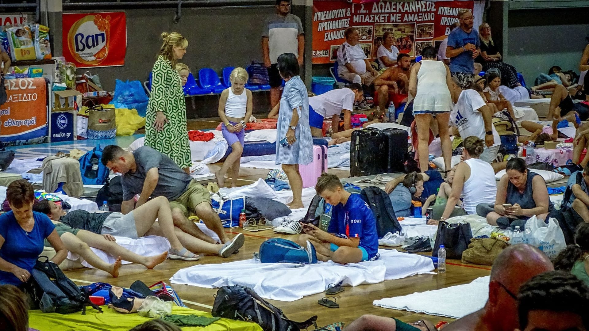 Viele Menschen halten sich in einem Stadion auf der griechischen Insel Rhodos auf, nachdem sie wegen katastrophalen Waldbränden in Sicherheit gebracht worden sind.