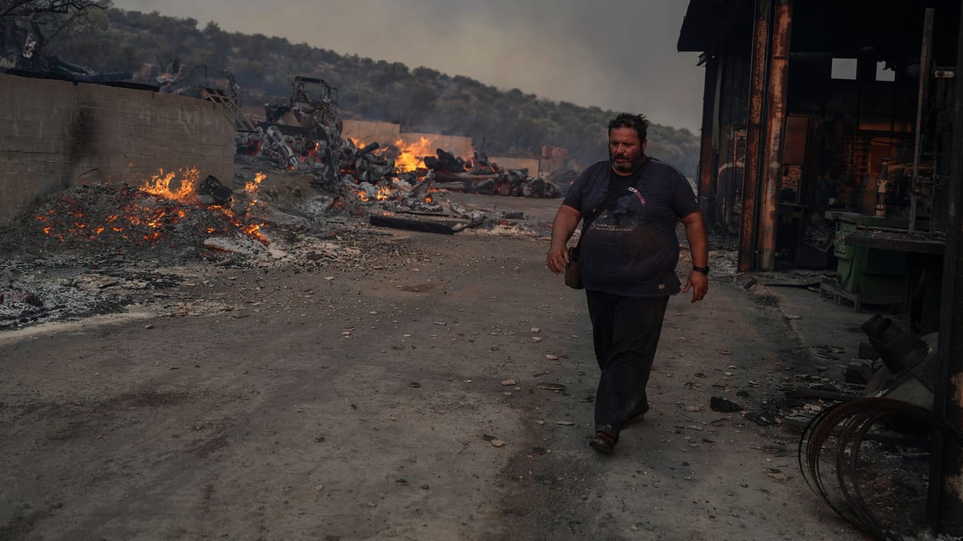 Thanassis Barberakis geht an der durch einen Brand zerstörten Werft seiner Familie in Mandra westlich von Athen vorbei: Am Montag waren zahlreiche Brände ausgebrochen.