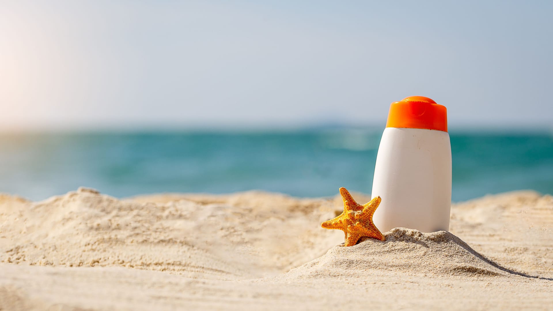 Eine Flasche Sonnencreme am Strand