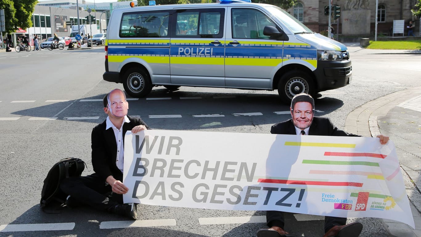 Sitzblockade in Göttingen: Klimaaktivisten der Gruppe "Letzte Generation" sitzen mit Masken von Bundeskanzler Scholz und Wirtschaftsminister Habeck auf einer Kreuzung.