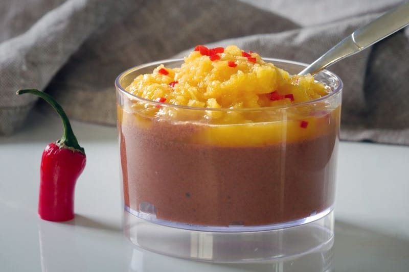 Für die vegane Mousse au Chocolat mit Mango & Chili wird geschmolzene Schokolade vorsichtig unter den Eischnee gehoben und kalt gestellt. Ein Püree aus frischer Mango, Saft und etwas Chili toppt den Schoko-Schnee.