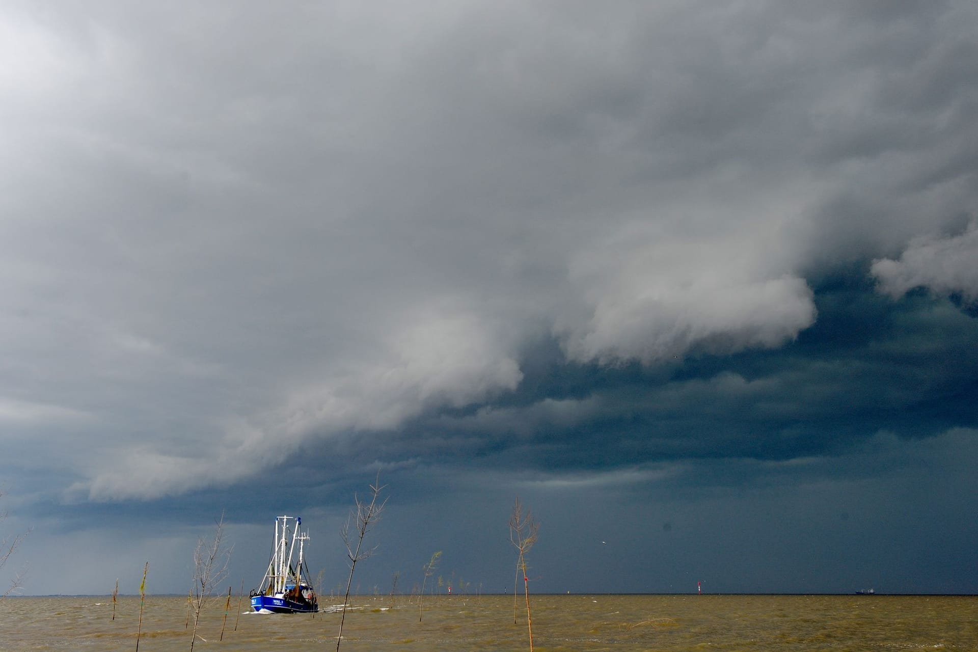 Gewitterfront an der Nordseeküste (Symbolbild): Ein Krabbenkutter kehrt vor einem heraufziehenden Gewitter in den schützenden Hafen zurück.