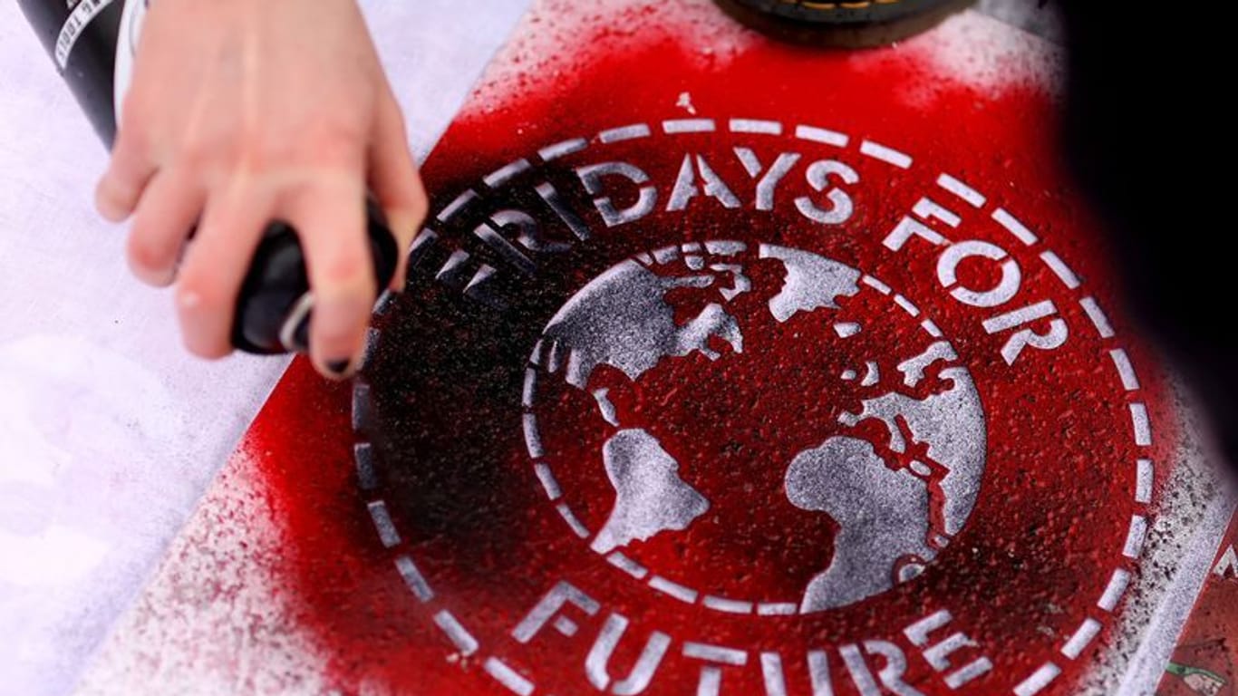 Eine Klimaaktivistin sprüht ein "Fridays For Future"-Logo auf ein Transparent (Archivfoto): Rund um die Bremer Ortsgruppe gab es zuletzt Antisemitismusvorwürfe.