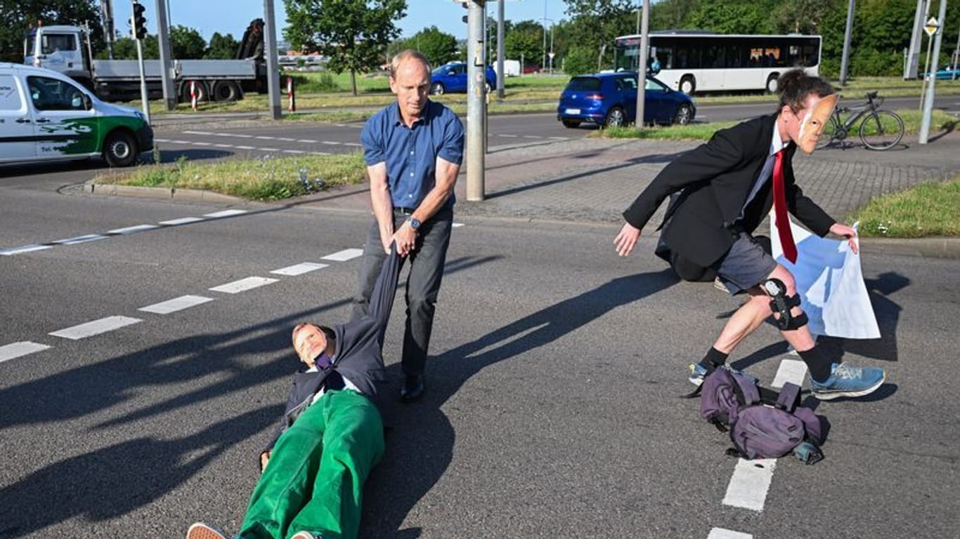 Ein Mitglied der Protestgruppe Letzte Generation wird bei einer Sitzblockade an der Autobahnabfahrt am Elbepark von einem Autofahrer (M) beiseite gezogen.