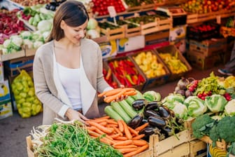 Eine Frau kauft Gemüse: Die Grundlage für einen gesunden Säure-Basen-Haushalt bildet eine vitaminreiche, vorwiegend pflanzliche Ernährung.