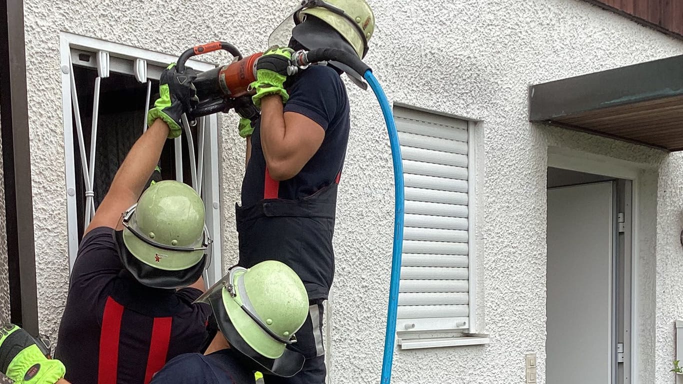 Mit einem hydraulischen Schneidegerät zwicken Feuerwehrleute das Eisengitter vor dem Fenster auf, um sich Zugang zur Wohnung zu verschaffen.
