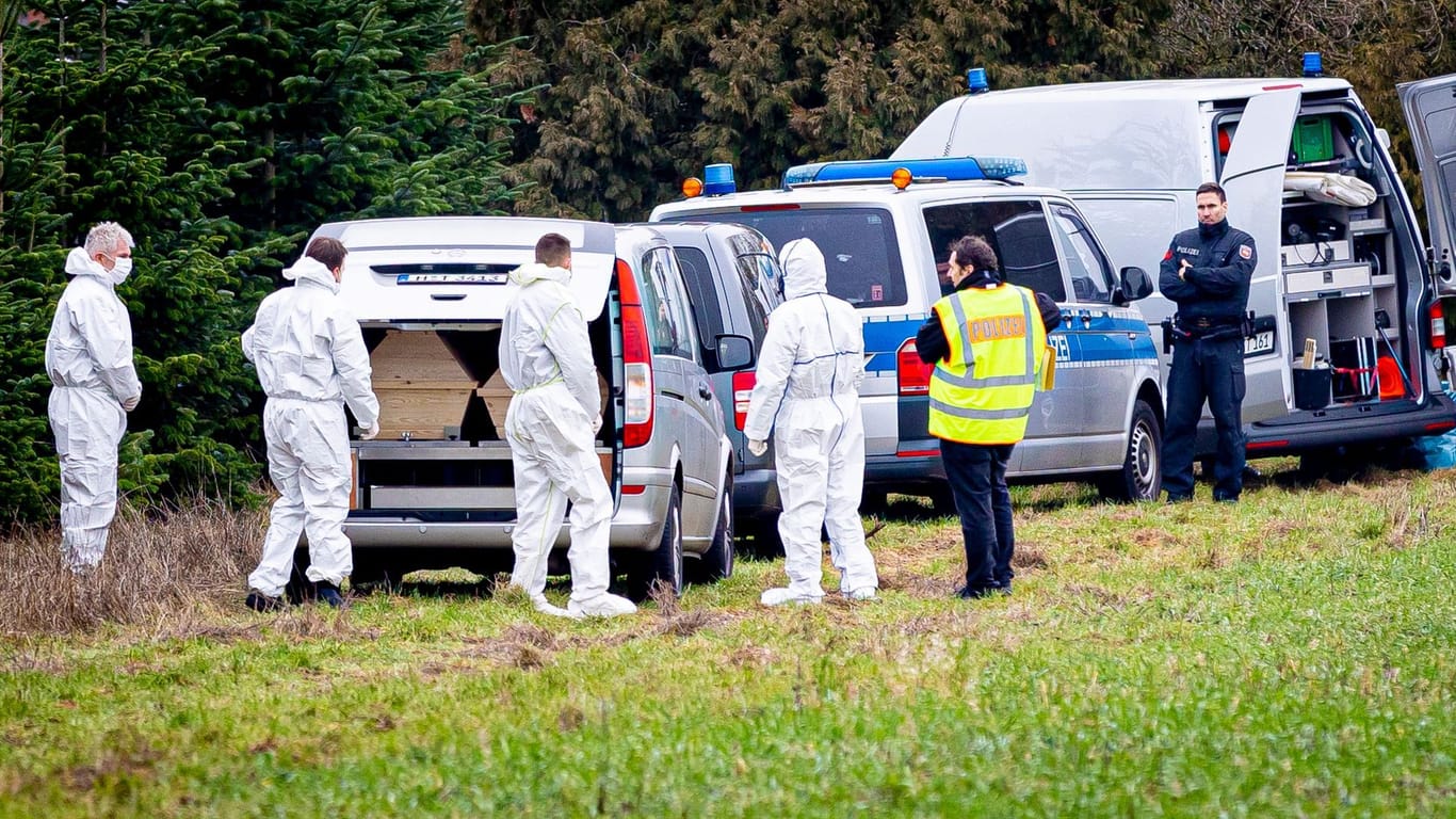 Mitarbeiter der Spurensicherung der Polizei stehen an einem Leichenwagen, der auf einer Wiese in Wunstorf parkt (Archivbild): In der Nähe wurde im Januar die Leiche eines 14-Jährigen gefunden.