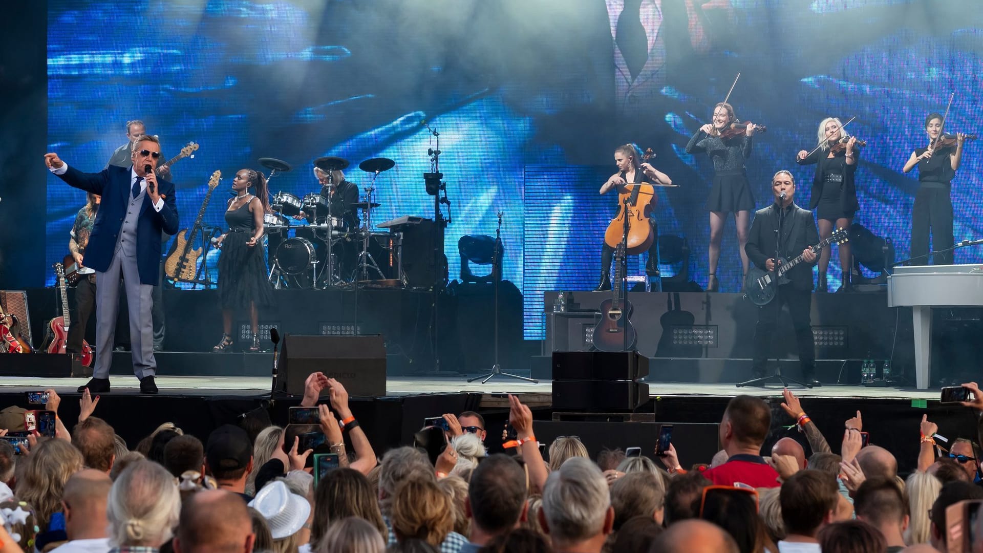 Roland Kaiser (l) spielt mit seinen Musikern zum Auftakt der «Kaisermania» 2023 auf der Bühne am Elbufer. All seine fünf open-air-Konzerte in Dresden auf dem Filmnächteareal gegenüber der historischen Dresdner Altstadt sind ausverkauft.