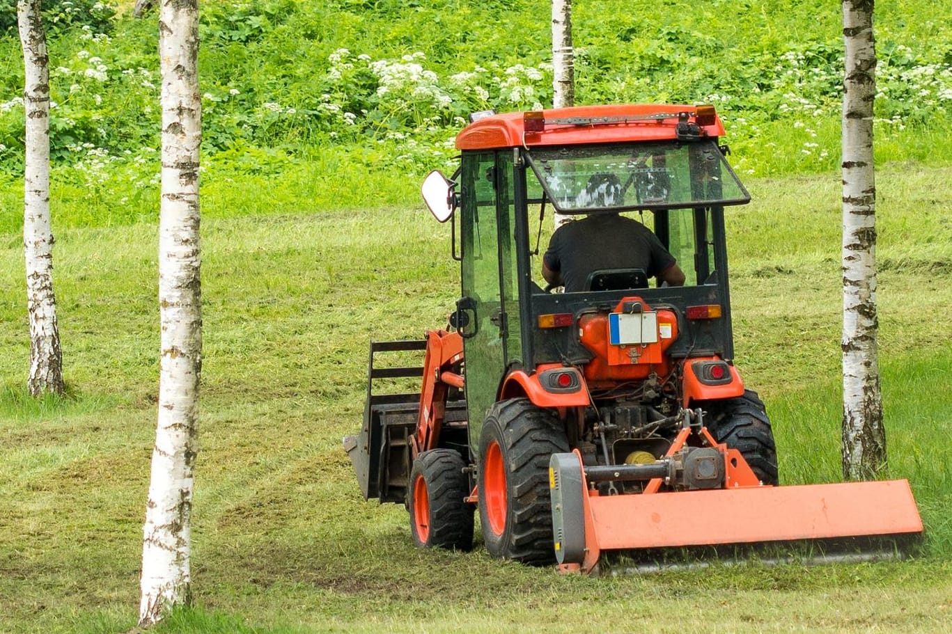 Traktor mit Rasenmäheranhänger (Symbolbild): Eine Frau in den USA ist unter eine solche Maschine geraten.