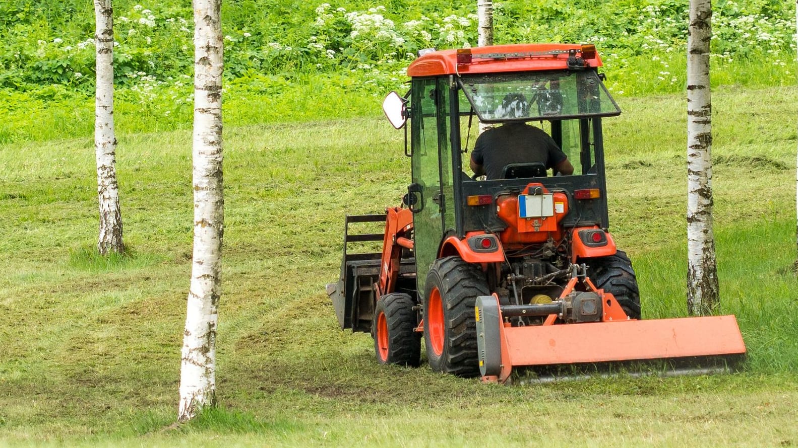 Traktor mit Rasenmäheranhänger (Symbolbild): Eine Frau in den USA ist unter eine solche Maschine geraten.