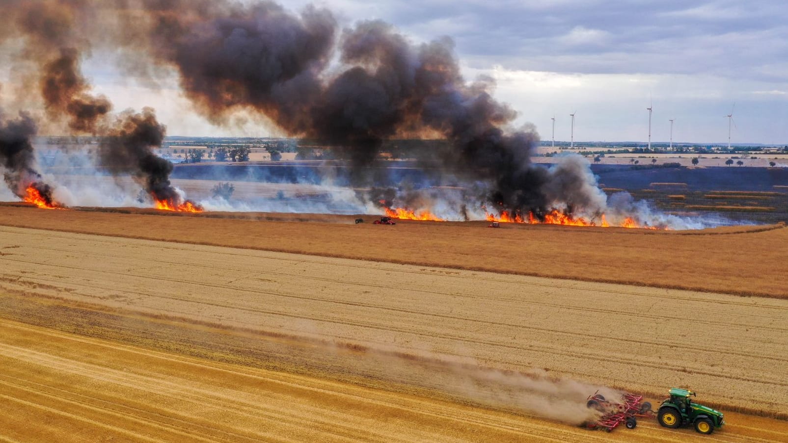 Mit einem Traktor pflügt ein Landwirt einen Schutzstreifen: Das Getreidefeld steht in Flammen. Mit einem Traktor pflügt ein Landwirt einen Schutzstreifen: Das Getreidefeld steht in Flammen.