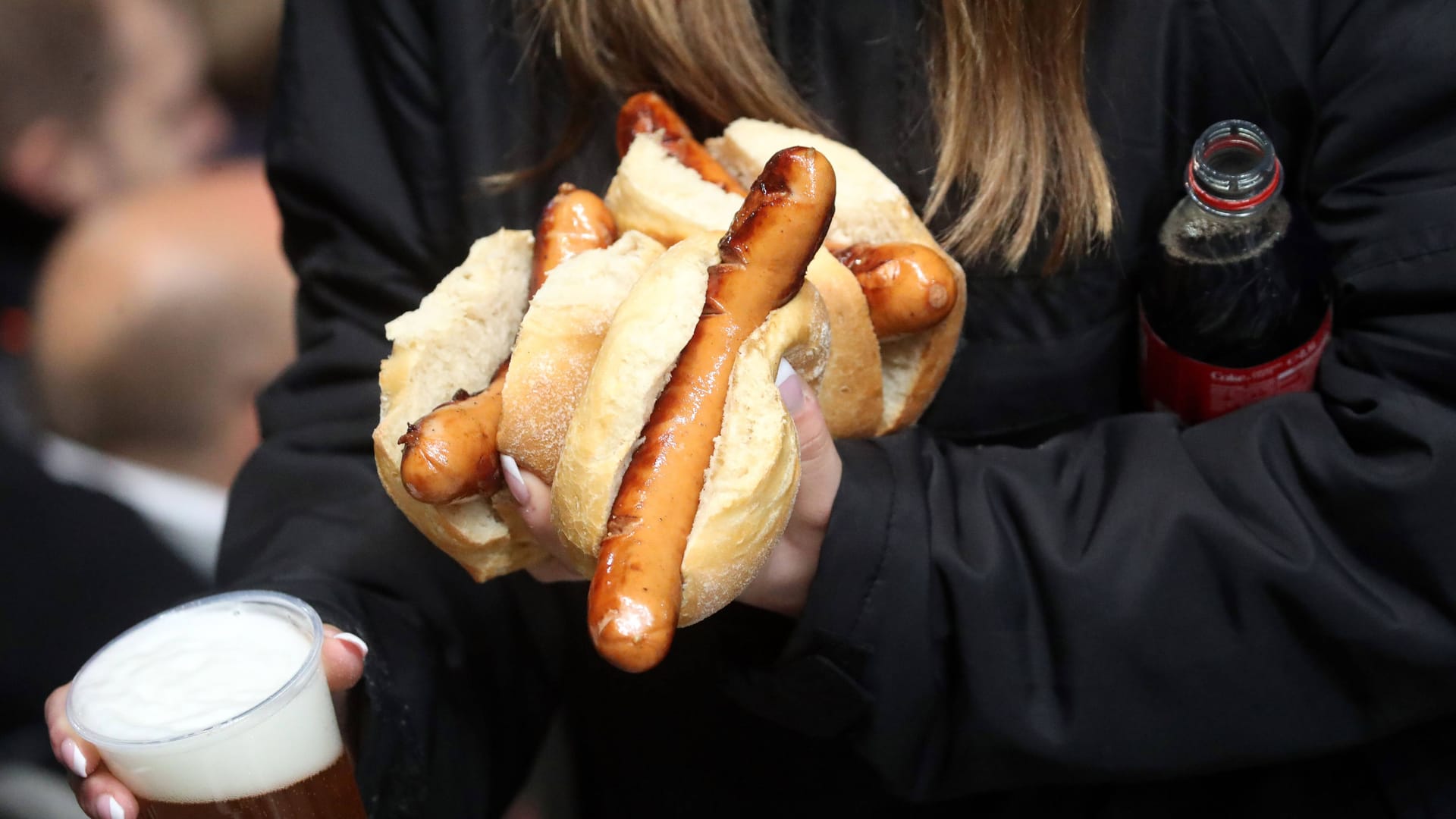 Ein Fan mit Bier und Bratwurst: Etwa 10.000 Würste werden nach Angaben des FC St. Pauli bei einem Heimspiel verspeist.