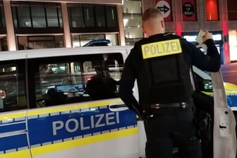 Polizist an Polizeiwagen (Symbolbild): Ein Beamter musste seinen Dienst vorzeitig abbrechen.
