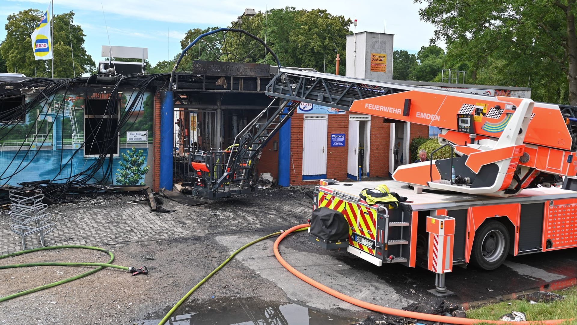 Eine Drehleiter der Feuerwehr steht vor dem Eingang des Schwimmbads. Die Ermittler gehen davon aus, dass das Feuer vorsätzlich gelegt worden sein könnte.