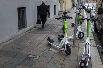 Eine Person läuft an abgestellten Elektrorollen in Berlin vorbei (Symbolfoto): Vielen Bürgern sind die wild abgestellten Scooter ein Dorn im Auge.