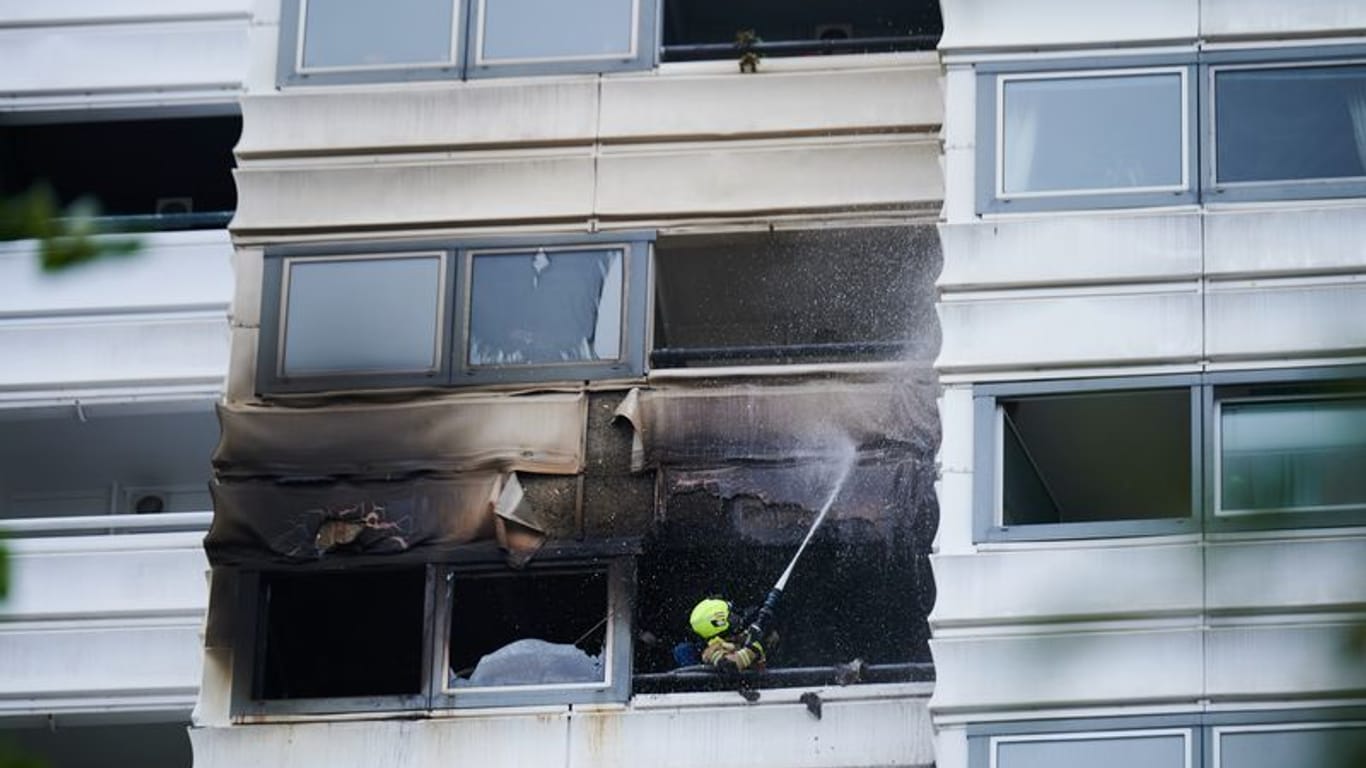 Ein Feuerwehrmann löscht die letzten Überreste der Fassade: Die Wohnung lag in 30 Metern Höhe.