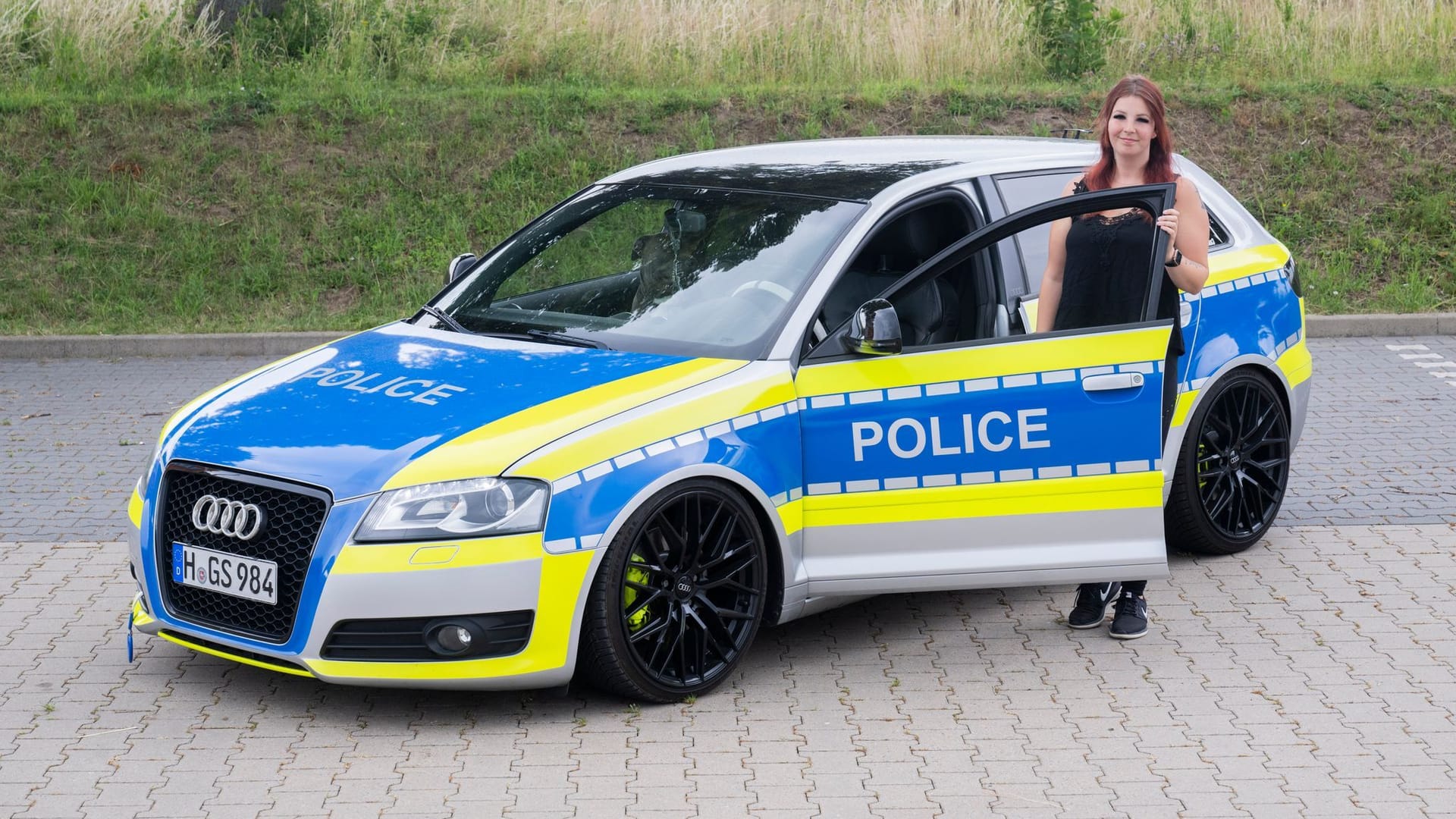 Auto-Tunerin Svenja Geertz steht neben ihrem Audi, der ähnlich wie ein Polizeifahrzeug foliert ist.