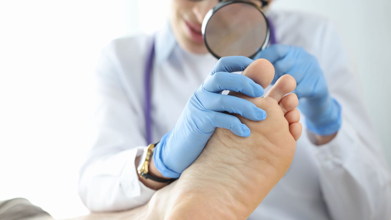 Eine Hautärztin untersucht den Fuß einer Frau.