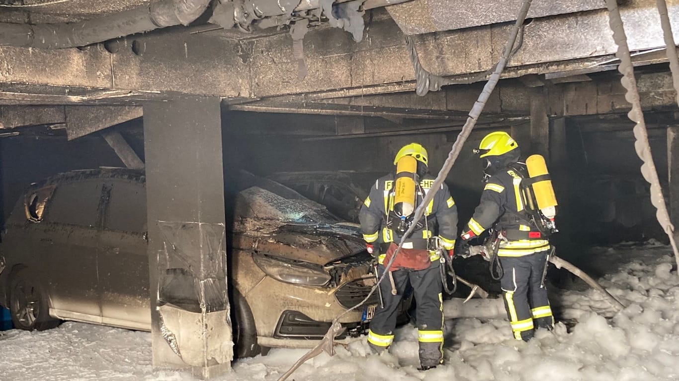 Zwei Feuerwehrleute stehen nach dem Brand in der Tiefgarage: Aus bislang unbekannter Ursache war ein Auto in Brand geraten.