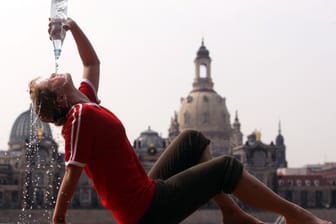 Eine Frau gießt sich vor der Dresdner Frauenkirche zur Abkühlung eine Wasserflasche über den Kopf (Archivbild).