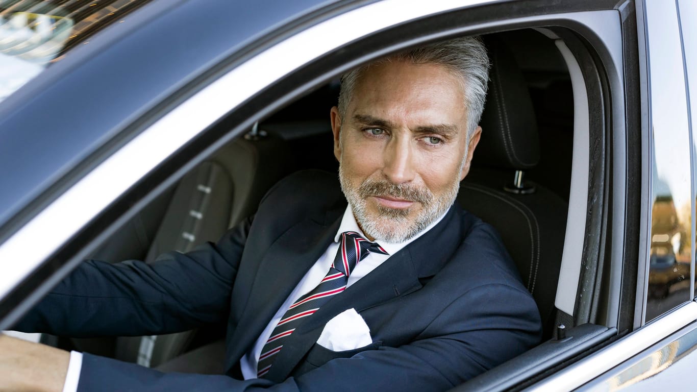 Ein erfolgreicher Geschäftsmann sitzt in einem schicken Auto (Symbolbild): Gutverdiener werden geringwertschätzt, kritisieren manche.