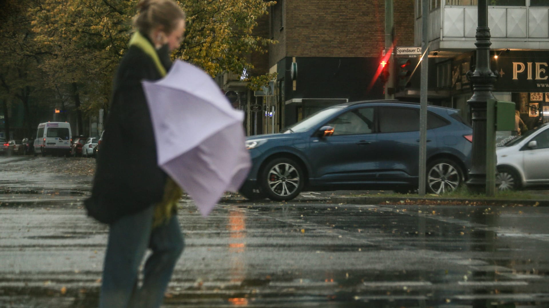 Frau mit Regenschirm im Sturm (Archivbild): In Berlin kann es phasenweise ungemütlich werden.