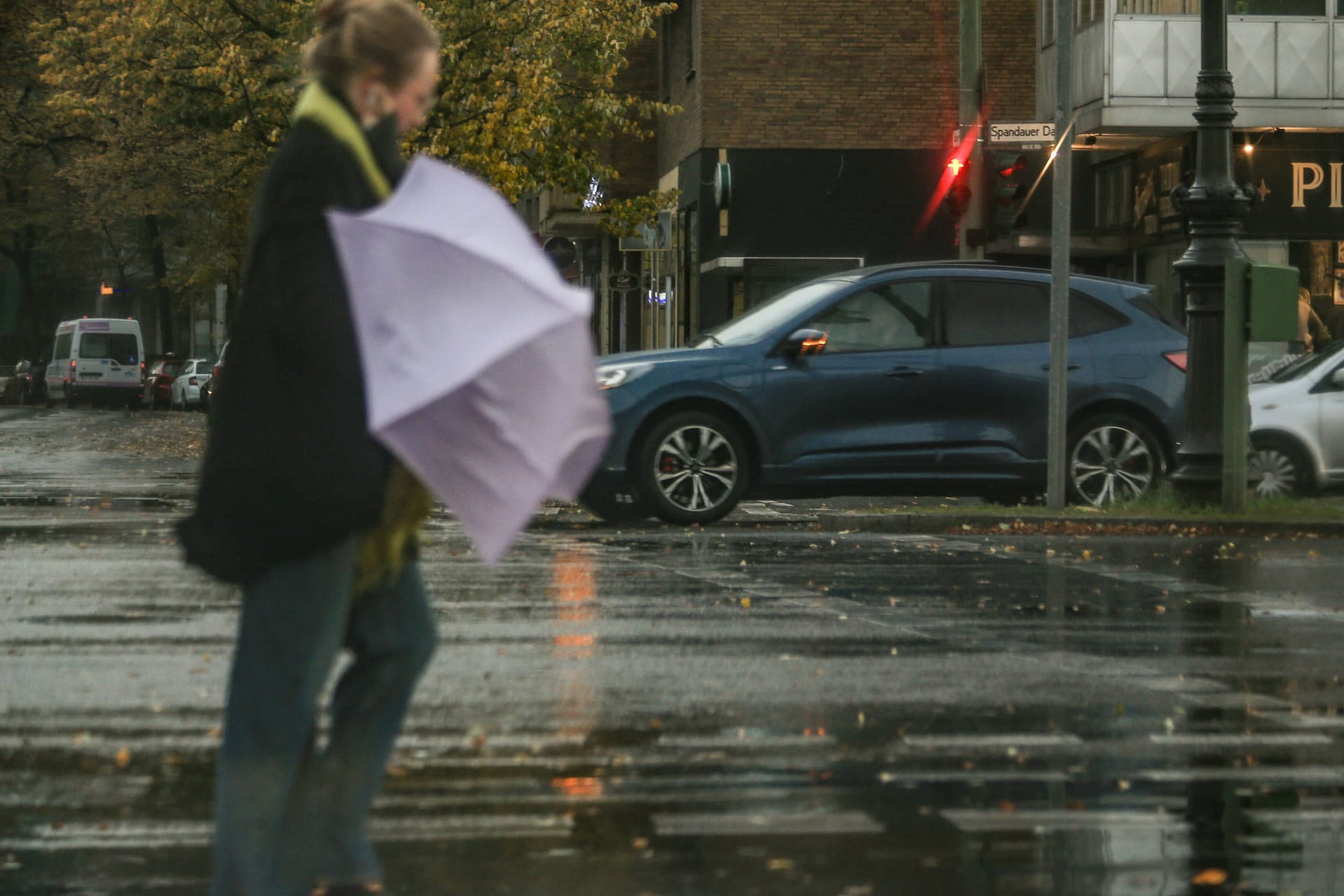 Frau mit Regenschirm im Sturm (Archivbild): In Berlin kann es phasenweise ungemütlich werden.