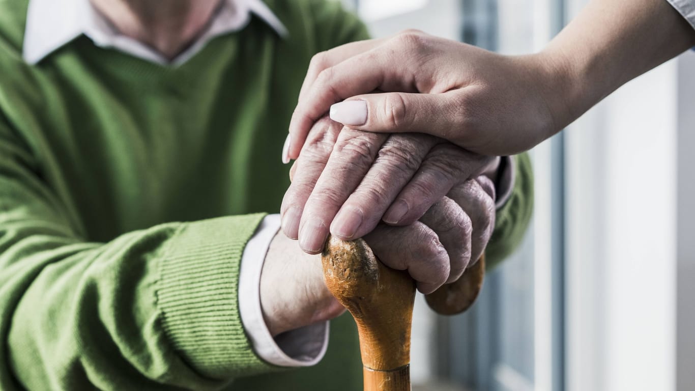 Eine Pflegekraft legt ihre Hand auf die eines Patienten (Symbolbild): In 70 Fällen soll ein Pfleger Bewohner einer Einrichtung missbraucht haben.