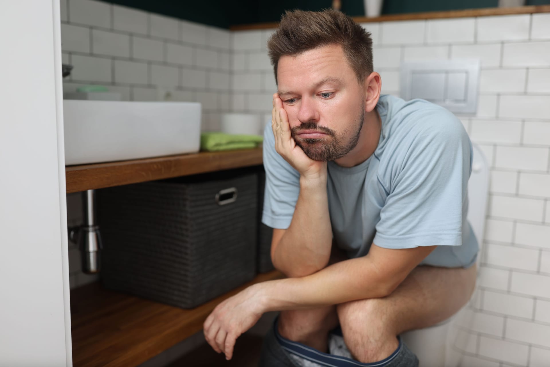 Mann sitzt nachdenklich auf der Toilette