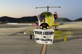 Klimaaktivist mit einem Banner auf dem in Englisch steht: "Euer Luxus ist unsere Klimakrise".