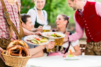 Ein Kellner serviert eine zünftige Brotzeit (Symbolbild): Biergärten sind nicht nur in Bayern im Sommer sehr beliebt.