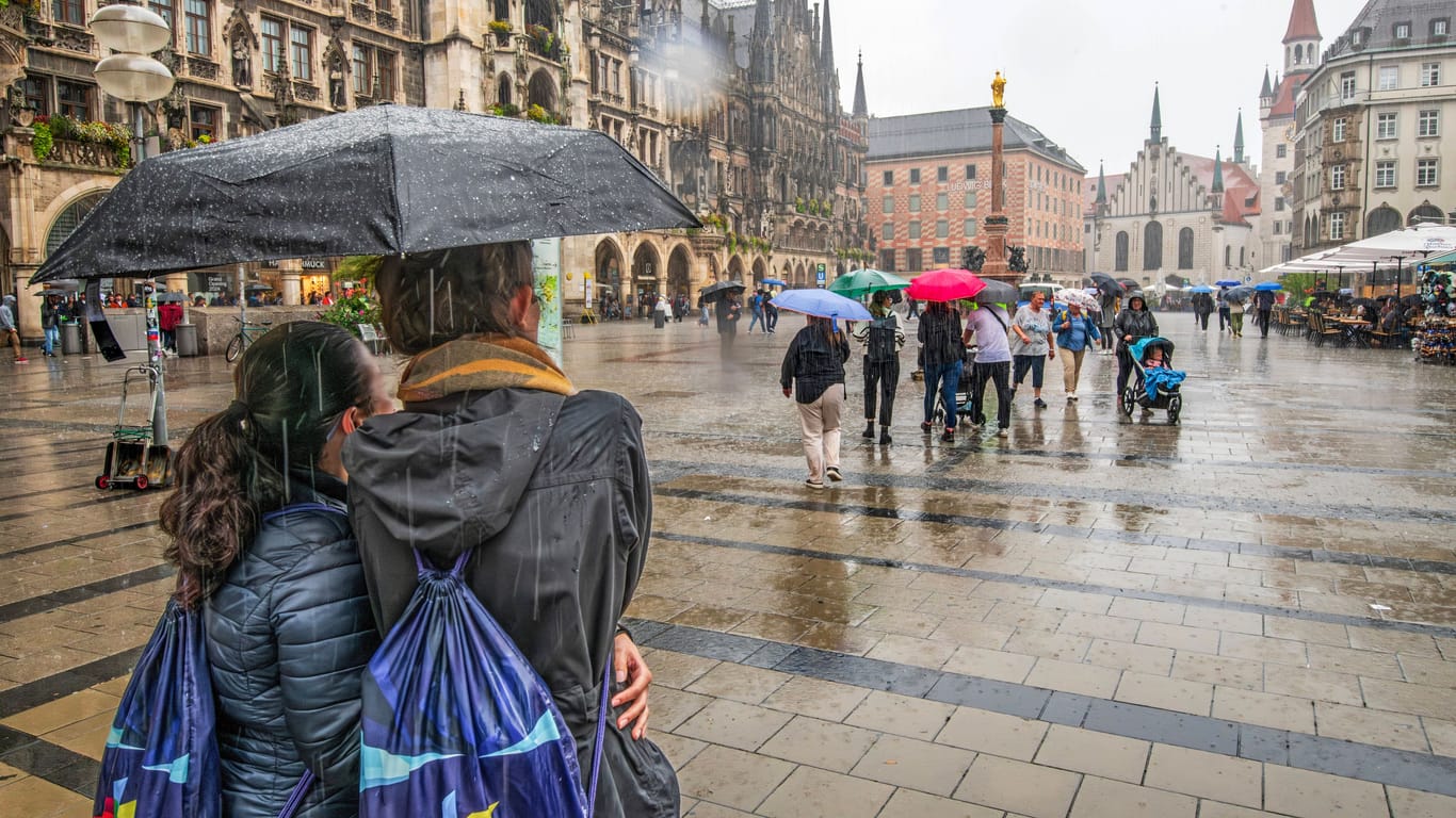Menschen stehen mit Regenschirm auf dem Marienplatz (Symbolbild): Am Wochenende könnte es in Bayern ungemütlich werden – auch in München.